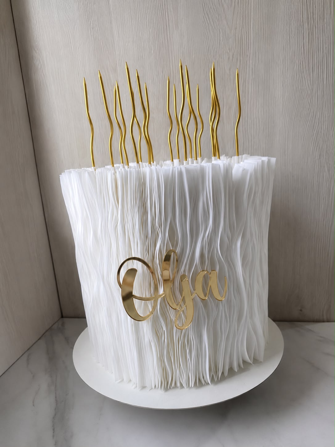 Bijela svečana torta sa zlatnim detaljima i imenom Olja.